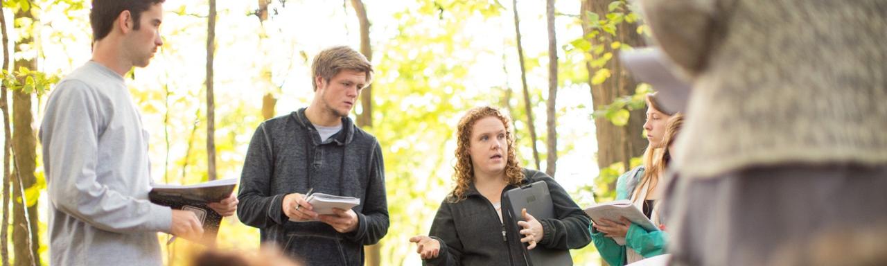 Group of students listening to woman and taking notes